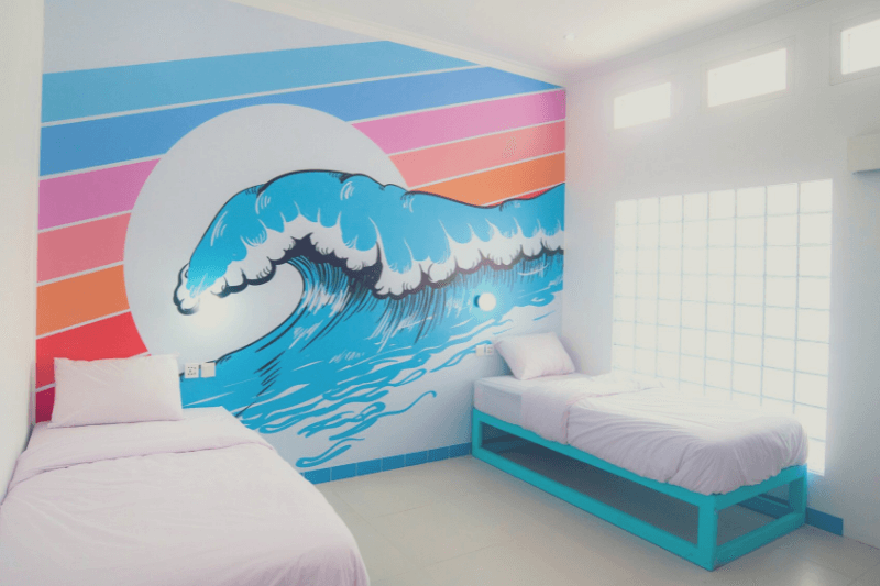 Private twin room at Mad Monkey with colorful wave mural and poolside views