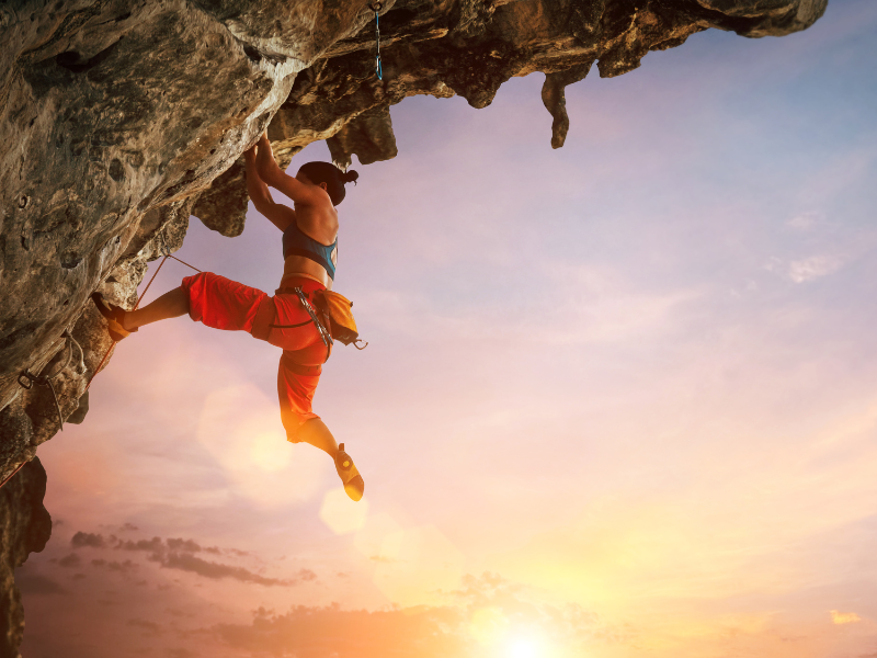 Woman rock climbing during sunset